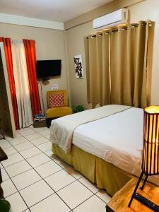 a hotel room with a bed and a chair at City Garden Apartment in Belize City