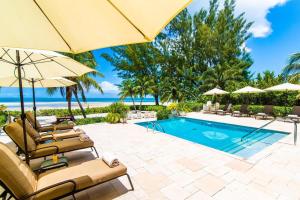 a pool with chairs and umbrellas next to the ocean at Moon Kai home in Driftwood Village