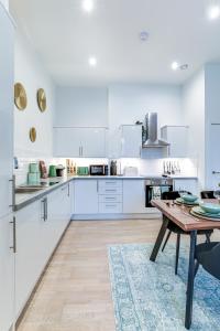 una cucina con armadi bianchi e tavolo in legno di Hemel Hampstead long-stay Residences a Hemel Hempstead