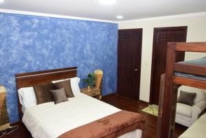1 dormitorio con cama y pared azul en Hostería La Travesía Campiña en Cuenca