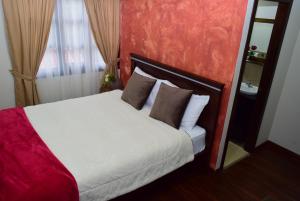 una camera da letto con letto bianco e cuscini marroni di Hostería La Travesía Campiña a Cuenca