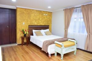 a bedroom with a bed and a yellow wall at Hostería La Travesía Campiña in Cuenca