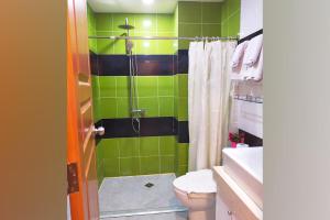 a green and black bathroom with a toilet and a shower at AMORE HOTEL MANILA in Manila