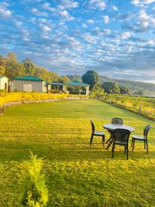 a table and chairs sitting in a field at Vasant Corbett Resort in Rāmnagar
