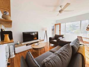 a living room with a couch and a tv at Harbourside Bliss: 2-Bedroom Coastal Apartment in Wollongong