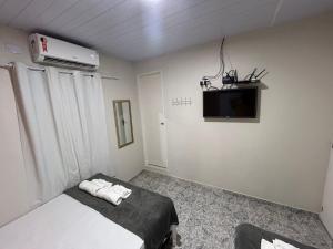 - une chambre avec un lit et une télévision murale dans l'établissement Suites Mar Azul, à São José da Coroa Grande