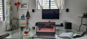 a laptop computer sitting on a glass table with a television at Breezy La Vista on the Terrace - Bridgetown, Kensington Oval - Cricket World Cup in Saint James