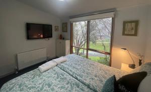 a bedroom with a bed and a large window at Halls Retreat - Luxury with a spa in Baw Baw Village