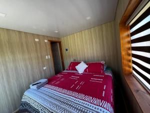 um quarto com uma cama com lençóis vermelhos e uma janela em Alojamiento Rustico Belloto (2) em Quilpué