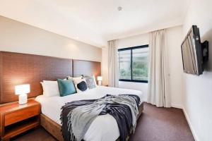 a bedroom with a large bed and a flat screen tv at Poolside Resort Living on Esplanade with Balcony in Darwin +18 photos
