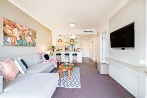 a living room with a couch and a tv at Poolside Resort Living on Esplanade with Balcony in Darwin