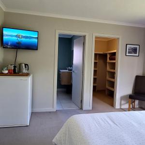 a bedroom with a bed and a television on the wall at Private guest room - no kitchen in Wanaka