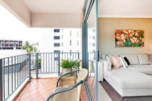 a living room with a couch on a balcony at Poolside Resort Living on Esplanade with Balcony in Darwin