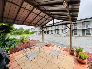 un patio con mesa y sillas bajo una pérgola en Colonial Lodge Motor Inn en Yass