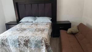 een slaapkamer met een bed en een bank bij Cabaña de lujo con Terraza para eventos in San José del Puente