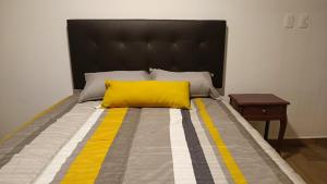 Una cama grande con una almohada amarilla. en Departamento loft súper ubicado. en Orizaba