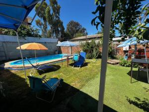 a yard with chairs and an umbrella and a swimming pool at Alojamiento Rustico Belloto 1 in Quilpué