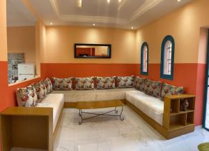 sala de estar con sofá grande y pared de color naranja en Spacious 3-Floor Riad en Marrakech