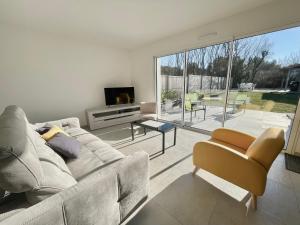 un soggiorno con un divano e una grande finestra di Maison familiale récente avec jardin, plage et commerces à pied, 6 couchages, WIFI, parking privatif - FR-1-231-297 a Brem-sur-Mer