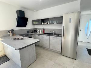 una cucina con un grande frigorifero in acciaio inossidabile di Maison familiale récente avec jardin, plage et commerces à pied, 6 couchages, WIFI, parking privatif - FR-1-231-297 a Brem-sur-Mer