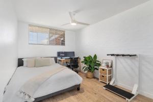 1 dormitorio con 1 cama y escritorio con ordenador en Newly renovated beach front unit. Views to die for!, en Alexandra Headland