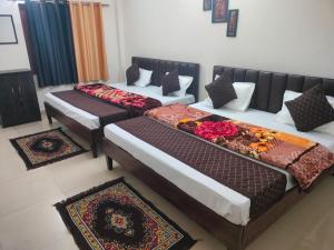 three beds in a room with mats on the floor at Hotel The Ramam in Ayodhya