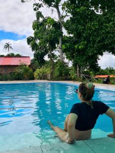 una donna seduta sul bordo di una piscina di Milía Amazon Lodge a Iquitos