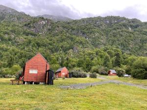 a red barn in a field in front of a mountain at Refugio Río Roberto in Villa Santa Lucía