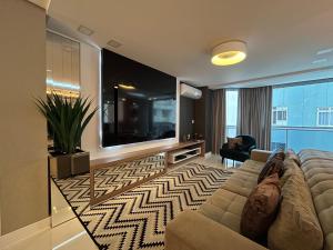 sala de estar con sofá y TV de pantalla plana grande en Beira Mar com Excelente Localização, en Balneário Camboriú
