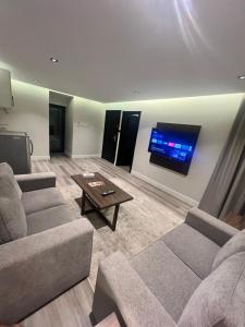 een woonkamer met 2 banken en een flatscreen-tv bij Amwaj Alshatie Furnished Units in Dammam