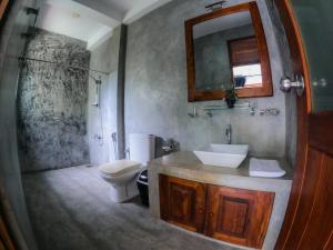 a bathroom with a sink and a toilet and a mirror at Hotel Athgira in Udawalawe +40 photos