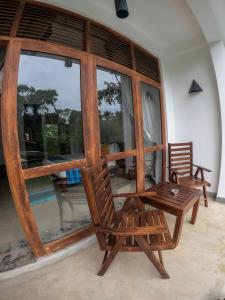 a room with two chairs and a table and windows at Hotel Athgira in Udawalawe