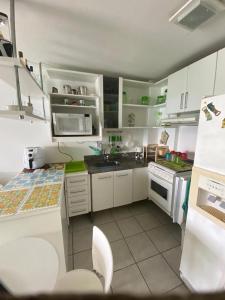una pequeña cocina con armarios blancos y electrodomésticos blancos en Porto Real Resort 90m2 - 3 Cômodos frente MAR! TOP, en Mangaratiba