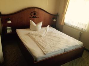 a white bed with a wooden headboard and two pillows at Hotel Goldner Loewe in Bad Köstritz