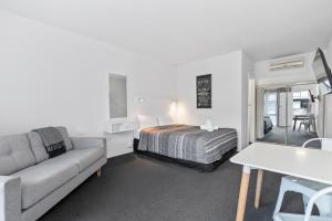 奥尔伯里Comfort Inn Commodore Albury的一间卧室，里面有一张床、一张沙发和一张桌子