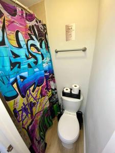 a bathroom with a toilet and a colorful shower curtain at Cozy & Colorful Miami Art Canvas w/HotTub & Murals in Miami