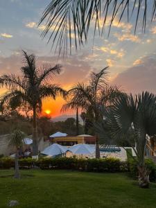 a sunset over a resort with palm trees and a pool at Cabaña de lujo con Terraza para eventos in San José del Puente
