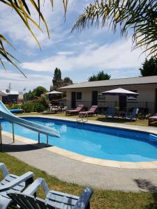 - une piscine avec des chaises longues et des tables dans l'établissement Tasman Motor Camp, à Tasman