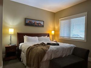 ein Schlafzimmer mit einem Bett, einem Fenster und einem Stuhl in der Unterkunft Solara Mountain Retreat - Pool - Hot Tub - Spa - Gym in Canmore