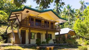 a yellow house with a balcony on top of it at High Chaparral Cottages in El Nido