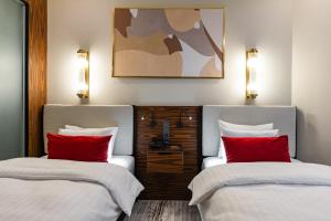 アルマトイにあるカザフスタン ホテルの赤い枕付きのベッド2台が備わる客室です。
