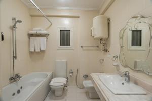 een witte badkamer met een bad, een toilet en een wastafel bij Zamalek Serviced Apartments by Brassbell in Caïro