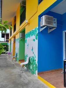 un edificio con una pared azul y amarilla con sillas en ลิตเติ้ลโฮม ที่พักเพชรบุรี en Phetchaburi