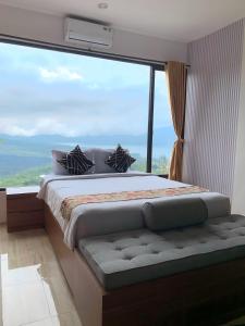 a bedroom with a bed in front of a large window at Devanora Hotel & Resto in Kintamani