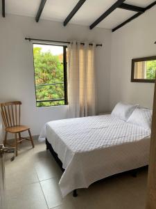 a bedroom with a bed and a chair and a window at Hermoso Apartamento en Medellín in Medellín