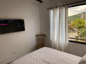 a bedroom with a bed and a window and a chair at Hermoso Apartamento en Medellín in Medellín