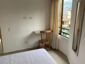 a bedroom with a bed and a chair and a window at Hermoso Apartamento en Medellín in Medellín