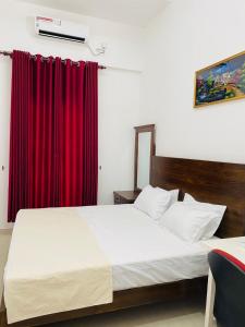 a bedroom with a large bed with red curtains at White Villa in Weligama