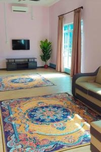 a living room with a couch and a rug at Teratak Kayu Homestay in Batu Pahat