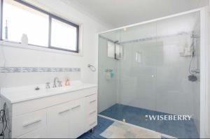 baño blanco con ducha y lavamanos en Luxurious and spacious home in taree, en Taree